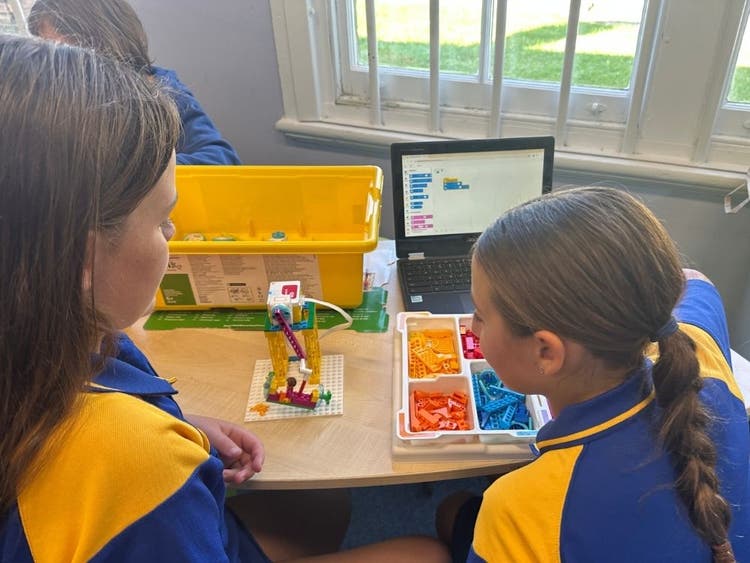 Two students coding lego spike prime robots