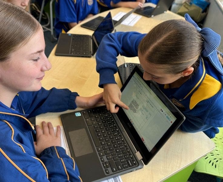 two students working on a laptop